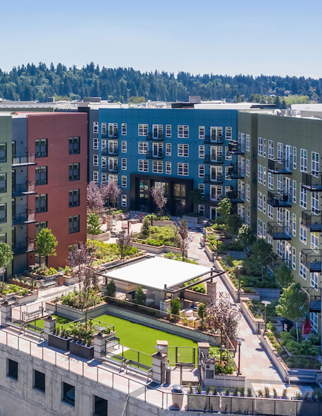 Aerial shot of the landscaping and outdoor amenities of a Fairfield apartment courtyard with tree-lined hills in the background.