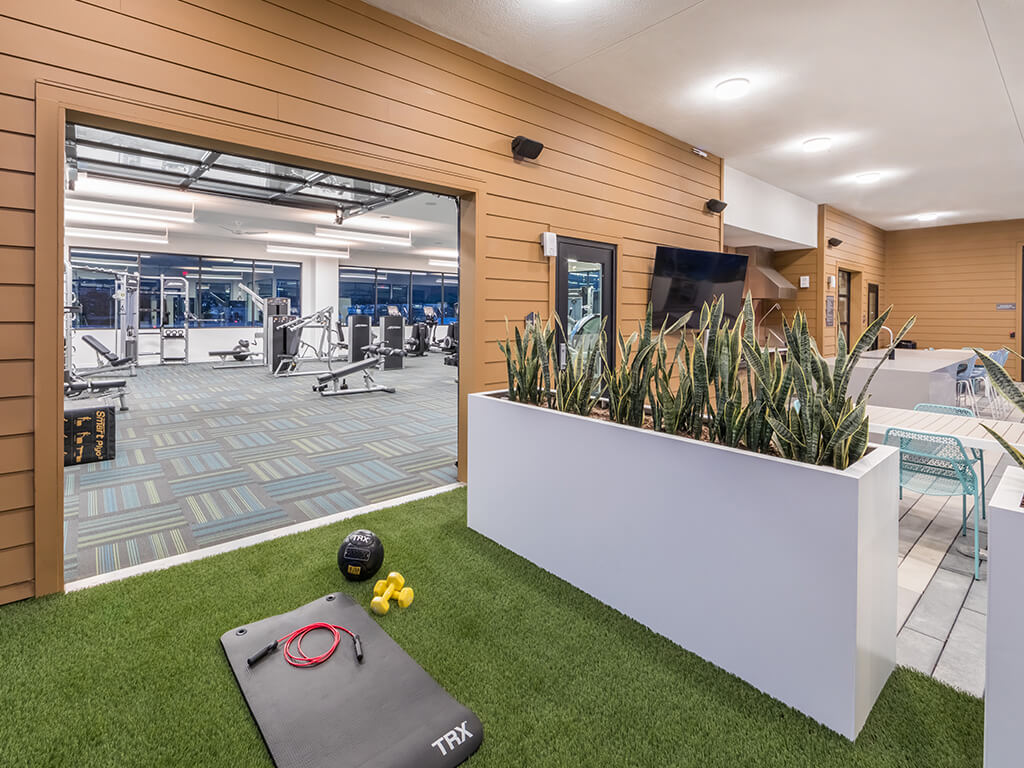 Artificial turf fitness area with exercise mat, jump rope and weights ready for use looks into Embark Apartment's rooftop-level fitness center with full suite of gem equipment.