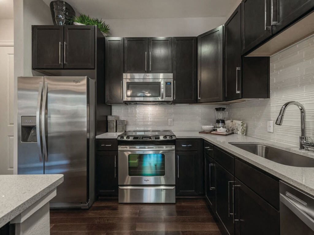 A modern kitchen with dark cabinets at the Ascent at CityCentre Apartments in Houston, Texas.