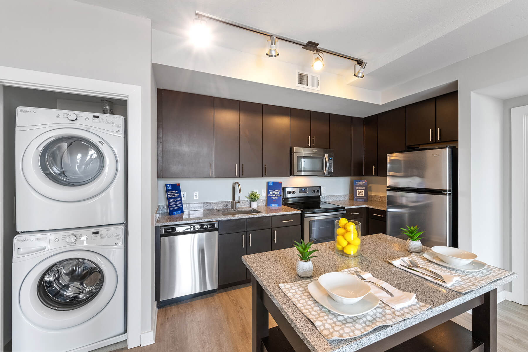 A kitchen with a kitchen island and laundry closet at the Bradley Braddock Road Station Apartments in Alexandria, Virginia.