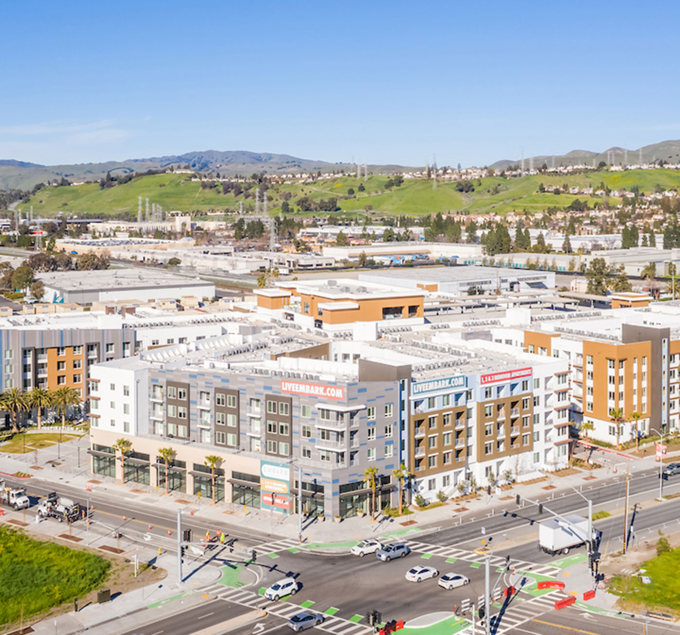 Aerial shot of the exterior corner of a Fairfield building under development with the street intersection in the foreground and lush hills behind.