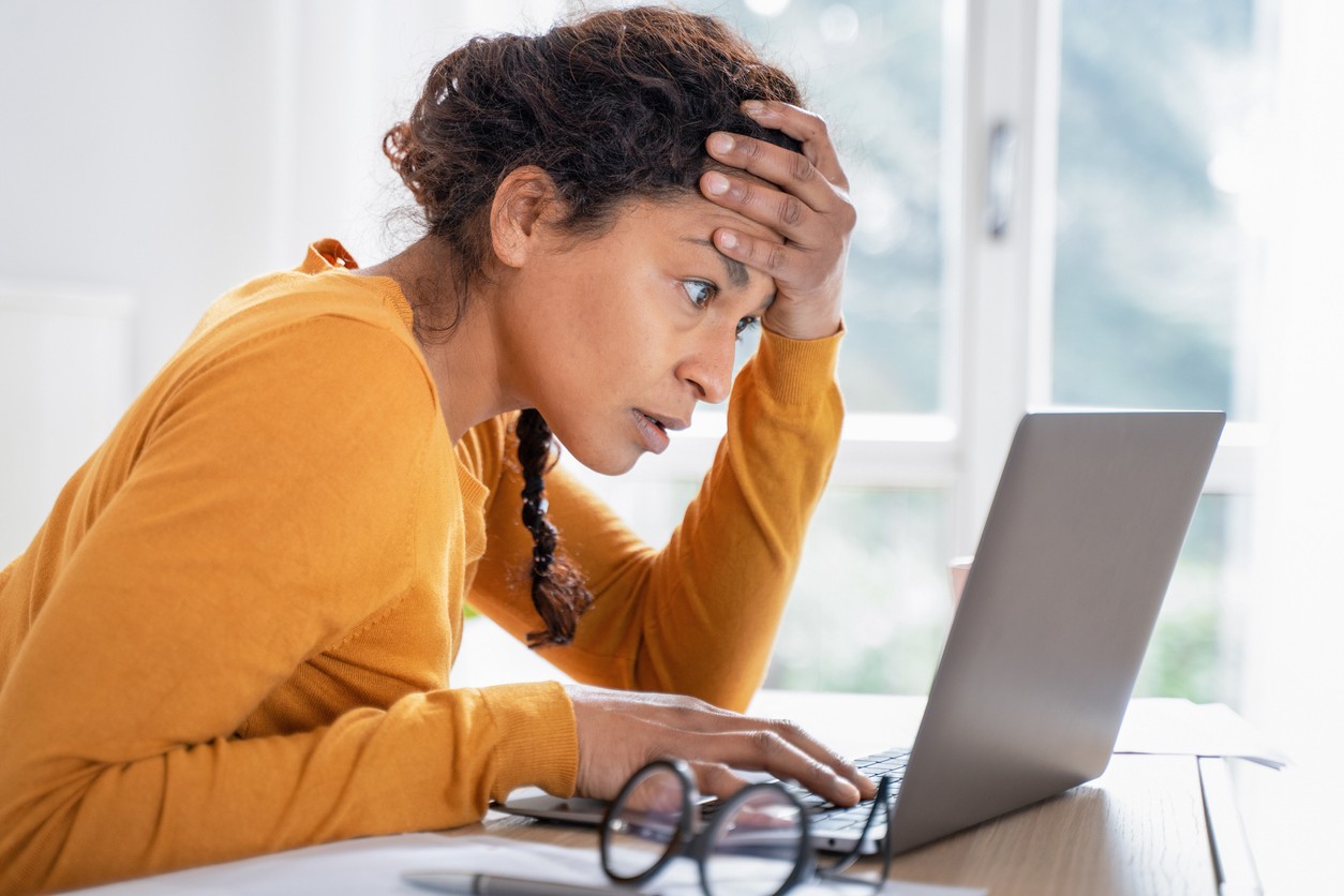 A frustrated woman looks at her open laptop