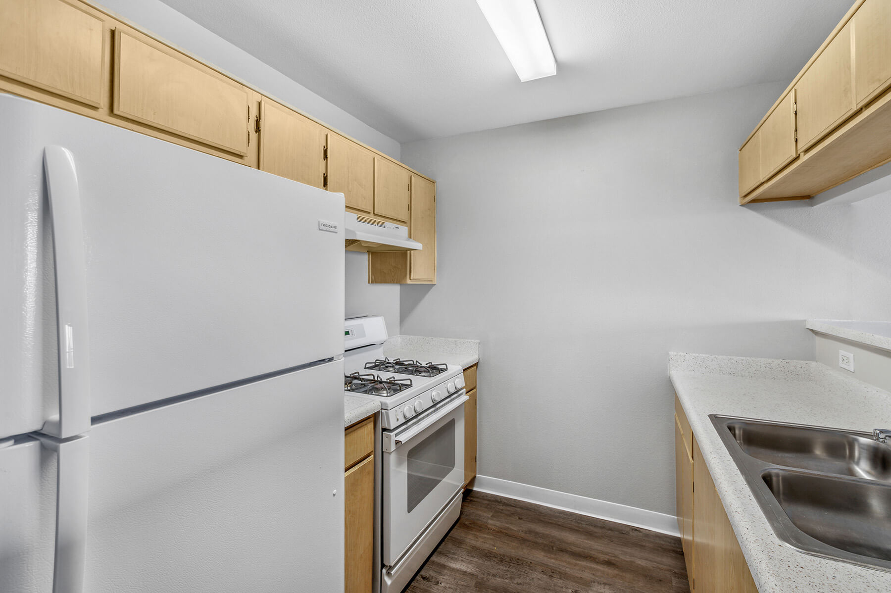 A white kitchen with wooden cabinets at the Harvard Yard and Glenmary Senior Affordable Apartments in Los Angeles, California.