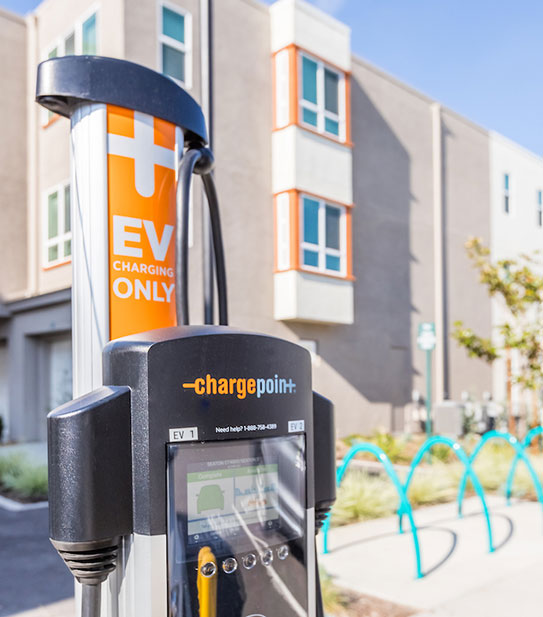An energy-efficient electric vehicle charger is stationed in a community parking with the building in the background promotes sustainability.